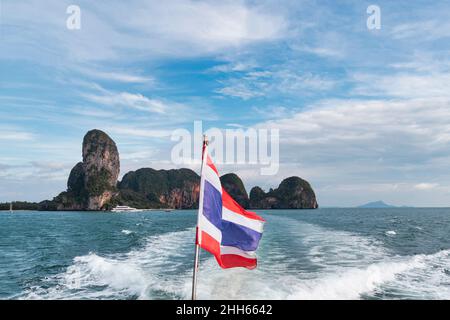 Thai Flagge über Boot's Wake auf dem Meer unter bewölktem Himmel Stockfoto