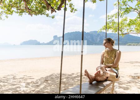 Frau sitzt auf einer Seilschaukel am Ao Nang Strand, Provinz Krabi, Thailand Stockfoto