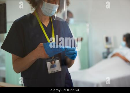 Krankenschwester mit Gesichtsschutz und OP-Handschuh Stockfoto