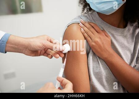 Arzt, der COVID-19-Impfstoff durch eine Spritze in den Arm des Patienten im Krankenhaus einspritzt Stockfoto