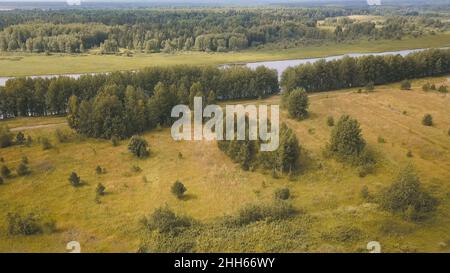 Draufsicht auf Straßen, die im Herbst am Fluss vorbeiführen und Bäume haben. Clip. Wunderschöne Herbstlandschaft mit Wald in der Nähe von schlammigem Fluss. Panorama des Waldes mit Straßen Stockfoto