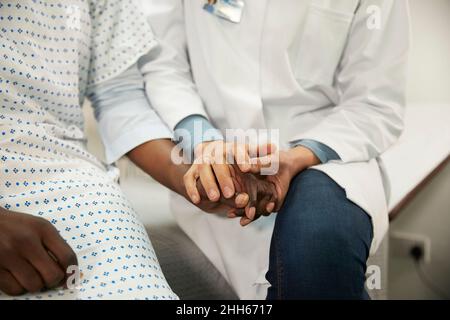 Arzt hält die Hände und tröstet den Patienten im Krankenzimmer Stockfoto