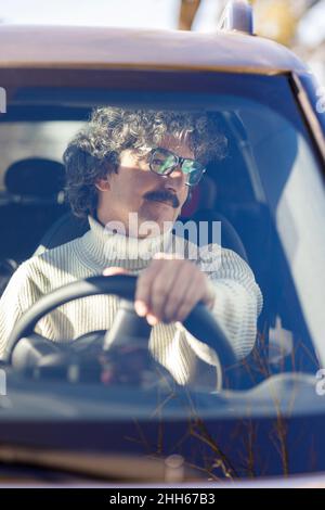 Nachdenklicher Mann mit Brillen, der das Auto durch die Windschutzscheibe fährt Stockfoto