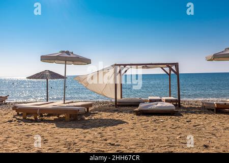 Leere Bänke und Sonnenschirme am Sandstrand Stockfoto
