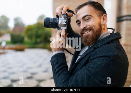 Lächelnder junger bärtiger Mann mit Kamera Stockfoto