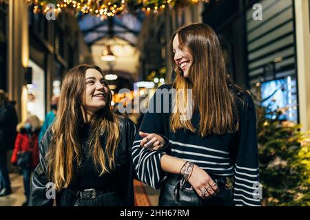Glückliche Freunde, die nachts Arm in Arm zusammen gehen Stockfoto