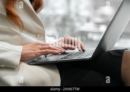 Hände einer arbeitenden Frau, die im Büro auf einem Laptop tippt Stockfoto