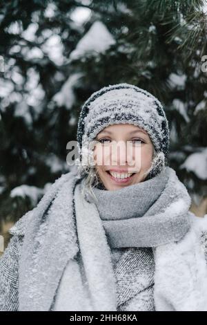 Glückliche Frau in schneebedecktem Strickhut im öffentlichen Park Stockfoto