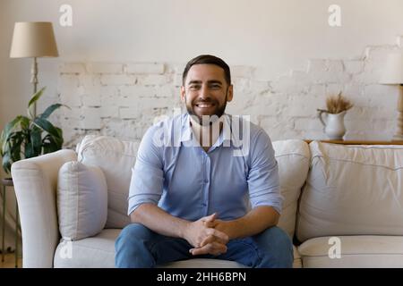 Glücklicher bärtiger Tausendjähriger Mann, der von zu Hause aus einen Videoanruf täte Stockfoto