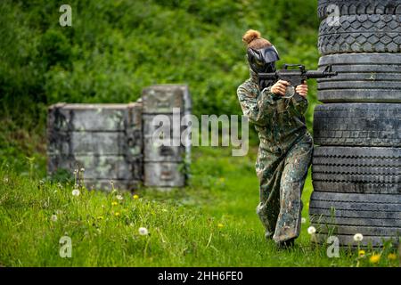 Junge Frau in Aktion beim Paintball spielen Stockfoto