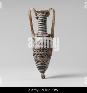 Glas Amphoriskos (Parfümflasche) 1st. Jahrhundert v. Chr. Griechisch, zypriotisch Durchscheinendes Grün, schwarz; ein Griff und Knopf an der Unterseite in Gelbbraun, der andere Griff in Gelbgrün; Spur in opakes Weiß.nach innen abfallende Randscheibe, mit Werkzeugeinrückung unten; hoch, leicht konkav, zylindrischer Hals; schräge Schulter; Länglicher piriformer Körper; großer auftragener Basisknopf; zwei Stangengriffe, die in Pads über die Schulter aufgetragen werden, leicht nach oben gezogen und über den Rand hinaus, dann ein- und heruntergeloopt und in einer doppelten Falte über der Traildekoration am Hals unterhalb des Randes befestigt werden.eine weiße Spur wird um die Lippe des Randes und aufgetragen Stockfoto