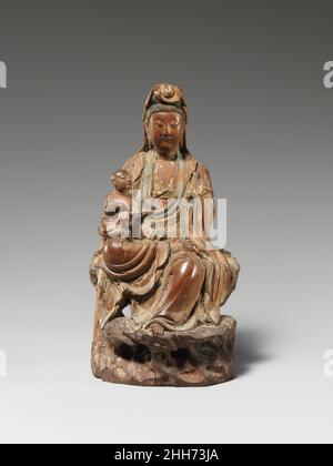 Guanyin der Bringer der Söhne 17th. Jahrhundert China der wertvollste Schatz im vormodernen China war ein Sohn, der das Familienerbe weiterführt. Diesen innig getragenen Wunsch widerspiegelnd, entstand eine neue Form von Guanyin, die den Bodhisattva als eine Schenkerin von Söhnen darstellte. Diese intime Skulptur, in der Guanyin den erhofften kleinen Jungen stellt, wäre von einem wohlhabenden Anhänger, der Mutter werden wollte, zur persönlichen Verehrung gemacht worden. Beachten Sie, dass das frühreiche Kind ein Buch hält – ein Zeichen dafür, dass es ein großer Gelehrter wird und dadurch das Ansehen der Familie fördert. Guanyin, der Bringer der Söhne. China. 17th ce Stockfoto