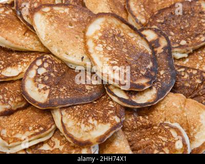 Viele hausgemachte kleine dicke Pfannkuchen aus der Nähe. Draufsicht. Traditionelles russisches Süßes Dessert. Stockfoto