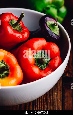 Bunte, frische Paprika in einer Schüssel auf einem Holzhintergrund Stockfoto