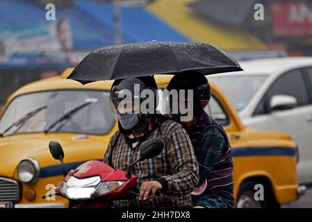 Kalkutta, Westbengalen, Indien. 23rd Januar 2022. Ein Pillionfahrer hält einen Regenschirm, während er bei Regenfällen in Kalkutta, Indien, am 23. Januar 2022, einen Roller fährt. (Bild: © Indranil Aditya/ZUMA Press Wire) Stockfoto