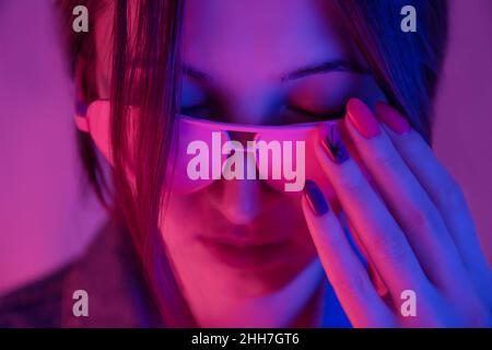 Retro Wave stilvolle junge Frau in rosa Sonnenbrille in Neonlicht. Stockfoto