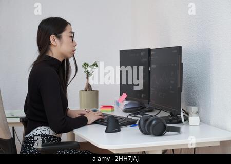 Junge asiatische Frau, die Daten, Grafiken und Berichte für Investitionszwecke analysiert. Stockfoto