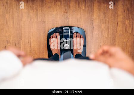 Frau, die sich auf einer Badezimmerwaage wägt. Diät Probleme Konzept Stockfoto