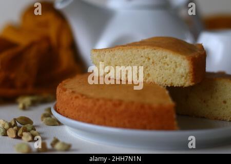 Scheibe Ghee-Kuchen. Eine Version von Teekuchen mit Ghee und Kardamom gewürzt. Perfekt zu einer Tasse heißen Tee. Aufgenommen auf weißem Hintergrund. Stockfoto