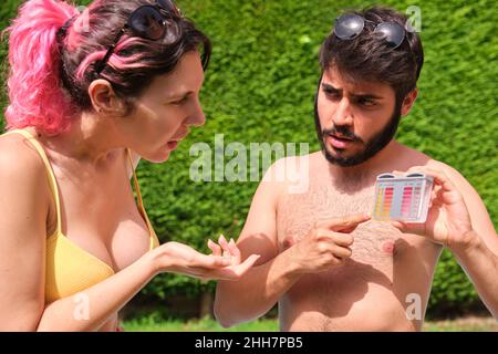 Junges Paar, das den ph- und CL-Wert seines Schwimmbades überprüft. Stockfoto