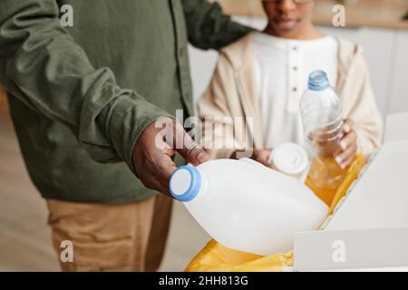 Nahaufnahme eines afroamerikanischen Vaters und Sohnes, der zu Hause Plastik in Recycling-Mülleimer legt, Kopierraum Stockfoto