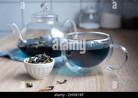 Glaskanne und Teekane mit Anchan aus Schmetterlingsblüten, Kräutertee auf dem Küchentisch. Stockfoto