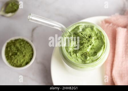 Dalgona Matcha Latte aus Schlagsahne mit grünem Teepulver und Milch im Glas auf weißem Hintergrund. Stockfoto