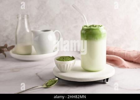 Geschlagener grüner Tee mit Milch, Dalgona Matcha Latte im Glas mit Matcha-Pulver auf weißem Hintergrund. Stockfoto