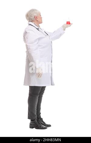 Seitenansicht einer Chemikerin in einem weißen Mantel mit farbigen Lösungen in Kolben in den Händen auf isoliertem weißem Hintergrund. Stockfoto