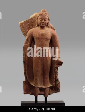 Stehender Buddha bietet Schutz Ende des 5th. Jahrhunderts Indien (Uttar Pradesh, Mathura) Dieses Buddha-Bild verkörpert die Qualitäten strahlender innerer Ruhe und Stille, die Produkte höchster Weisheit. Die Figur hob einmal seine rechte Hand (jetzt fehlt) in der charakteristischen abhaya-Mudra, eine Geste, die Angst zerstreut und Beruhigung vermittelt. Der Buddha wird in das einfache, ungeschnittenes Tuch eines Mönchs gekleidet, und seine Religiösität wird weiter durch einen großen Heiligenschein und verheißungsvolle Markierungen (Lakshanas), sowohl natürlich als auch übernatürlich, vermittelt, die Buddhaschaft (den Zustand vollkommener Erleuchtung) als die Summe von Styli bezeichnen Stockfoto