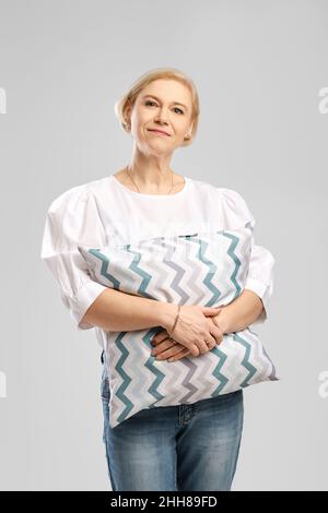 Ältere Frau umarmt weiches Kissen Stockfoto