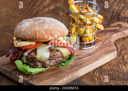 Cheeseburger mit Pommes auf Holz Stockfoto