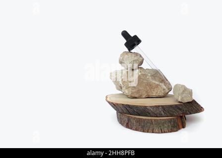 Eine kosmetische Glaspipette liegt auf einem Stein auf weißem Hintergrund. Das Konzept der Kosmetik, Schönheitsverfahren Stockfoto