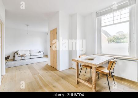 Ein Satz von Holzstühlen und Tisch in der Halle mit Holzboden und großem Fenster Stockfoto