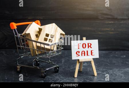 Warenkorb mit Häusern und Zeichen zum Verkauf geladen. Kauf und Verkauf von Wohnungen. Geld sparen in Immobilien, Investitionen in Wohnungen. Immobilienbewertung. Stockfoto