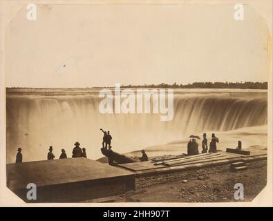 Niagarafälle Ca. 1855 Possibly by Silas A. Holmes American Diese Studie über die Niagarafälle strebt nach Erhabenheit, auch wenn sie in der Arbeitswelt der Besucher an einem beliebten Wahrzeichen begründet ist. Die Aussicht ist vom Table Rock auf der kanadischen Seite der Wasserfälle und könnte von Silas A. Holmes, einem beliebten New Yorker Fotografen von Sehenswürdigkeiten für den Tourismushandel, gemacht worden sein. Niagarafälle 282057 Stockfoto