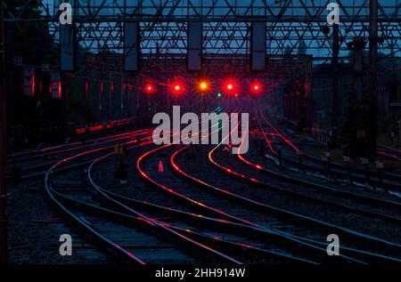 Blick nach Süden vom Bahnhof Preston aus, Westküsten-Hauptlinie die roten, gelben und grünen Bahnsignale reflektieren und leuchten auf der Strecke. Stockfoto