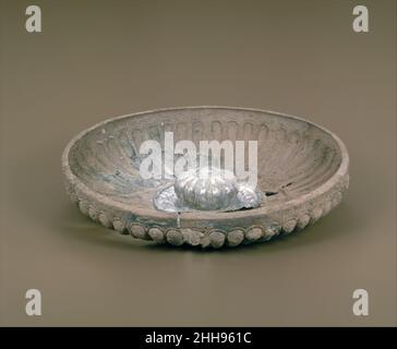 Silver Paliale (Libation Bowl) Ende 7th oder Anfang 6th Jahrhundert v. Chr. Ostgriechisch, vielleicht Rhodian Diese Schale ist die früheste der traditionellen Palialai des Museums mit einem ausgeprägten Omphalos (Nabel) oder Zentralboss; Die hohle Unterseite hatte einen Griff für zwei Finger, als die Pphiale gekippt wurde, um ein Trankopfer zu gießen. Stilisierte Lotoblüten sind auf der sanft geschwungenen Oberfläche der Schale eingraviert. Der Boss, dessen Kragen mit eingeprägten Tieren verziert war, war ursprünglich wie auf der angrenzenden Schale mit einer weiteren vergoldeten Metallschicht bedeckt. Silver phiale (Libation Bowl). Ostgriechisch, vielleicht Rhodian. Ende 7th oder Stockfoto