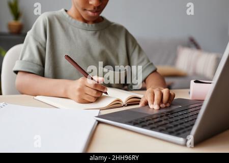 Eine kurze Aufnahme eines afroamerikanischen Jungen, der während des Studiums zu Hause einen Laptop verwendet, mit einem Konzept für die Heimuntersetzung Stockfoto