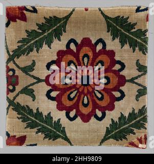 Fragment eines weißen Samtteppichs aus dem 17th. Jahrhundert Teppiche aus Blumen und Reben, die auf neutralen Hintergründen angeordnet sind, wurden in großer Zahl während der Herrschaft von Shah Jahan im 17. Jahrhundert hergestellt. Dieses Samtfragment war ursprünglich Teil einer solchen Komposition. Die große Blume in der Mitte bezieht sich auf die Technik der Pietra Dura, in der Edelsteine, die oft florale Motive darstellen, in Marmor in architektonischen Einstellungen eingelegt werden. Die diskreten Formen der festen, nicht schattierten Farbe, die die Blume bilden, erinnern an eine der Techniken, die in den eingelegten Steinen von Pietra d zu sehen sind Stockfoto