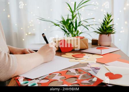 Frau, die zum Valentinstag einen Brief von Hand schreibt. DIY Handwerk Konzept Stockfoto