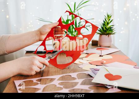 Frau Hände machen von handgefertigten Valentine Grußkarten. DIY, Handwerk Konzept, Geschenk mit eigenen Händen. Dekoration zum Valentinstag Stockfoto