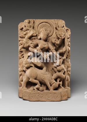Die Göttin Durga, die den Büffeldämon erschlagen hat (Mahisasura Mardini) 10th. Jahrhundert Indien (Rajasthan) die mehrarmige Durga trampelt den erschlagenen Büffel mit ihrem erhobenen Bein und stürzt ihren Dreizack in die menschliche Form des Dämons Mahisha, der aus dem Hals des Tieres hervortritt. Ihr Fahrzeug, der Löwe, schließt sich dem Kampf an und zermalmt den Büffel von hinten. In dieser feierlichen Ikone, die eine Außennische in einem Hindu-Tempel besetzen soll, wird Durga von Girlande-tragenden himmlischen Dienern (gandharvas) geehrt. Die Göttin Durga, die den Büffeldämon erschlugt (Mahisasura Mardini). Indien (Rajasthan). 10th Centu Stockfoto