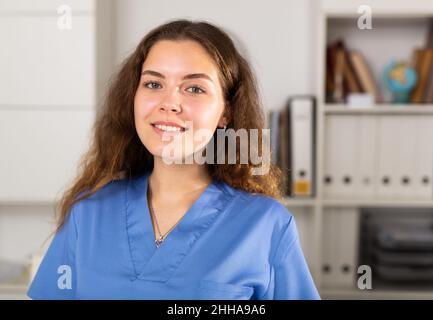 Positive Ärztin in blauem Hemd im medizinischen Zentrum stehend Stockfoto