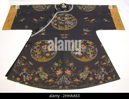 Woman's Informal Robe with Garden Roundels Early 18th Century China die Roundels auf dieser Robe zeigen Gartenfelsen mit Blumen, Früchten und glückverheißenden Elementen wie dem endlosen Knoten und Fledermäusen ( Fu, ein Homophon mit dem Wort für Glück). Am unteren Rand des Gewandes spielen zwei Paare chinesischer Löwen mit Beribonenkugeln in einem blumengefüllten Garten. Informelle Robe der Frau mit Garten-Rundeln 70383 Stockfoto