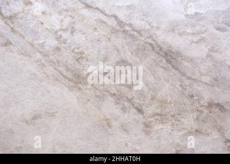 Hellgrauer Granit, flache Natursteinoberfläche mit braunen Adern aus nächster Nähe. Hintergrund, Muster, Textur. Stockfoto