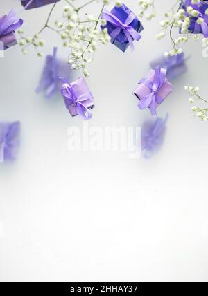 Eine mehrschichtige Postkarte aus Geschenkschachteln in einer modischen, trendigen, sehr perifarbenen Farbe mit weißen Blüten auf einem nebligen Hintergrund. Happy Women Day und Val Stockfoto