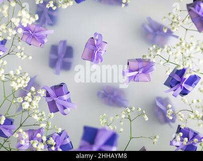 Eine mehrschichtige Postkarte aus Geschenkschachteln in einer modischen, trendigen, sehr perifarbenen Farbe mit weißen Blüten auf einem nebligen Hintergrund. Happy Women Day und Val Stockfoto