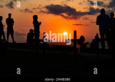 Silhouette von Menschen und Kreuzen, die auf dem Boden zu Ehren der von Covid-19 Getöteten befestigt sind. Sonnenuntergang in Salva Stockfoto