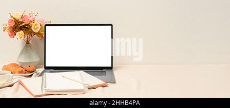 Eleganter, femininer Arbeitsplatz mit Laptop-Computermockup, Notebooks, Dekor und Kopierfläche auf weißem Tisch. Stockfoto